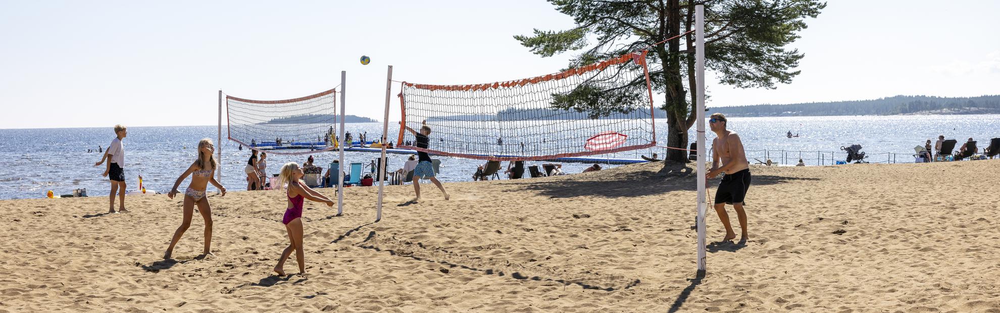 Personer som spelar beachvolleyboll på stranden