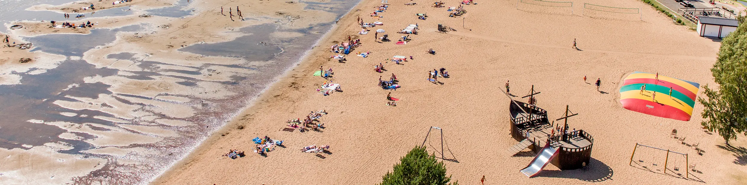 Flygbild över stranden med massa personer som ligger och solar