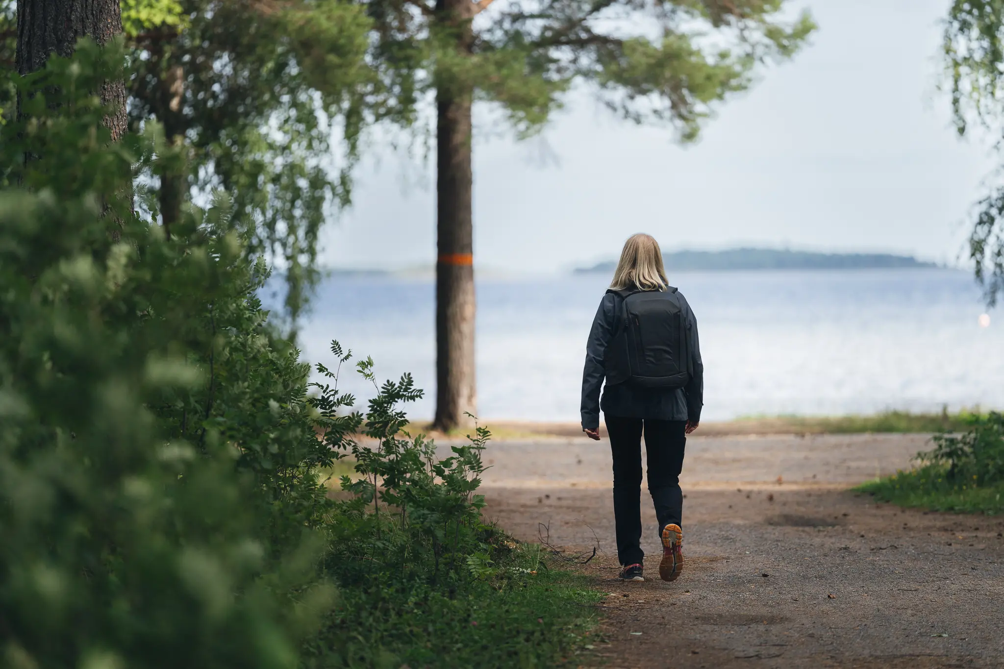 Närbild på kängorna på en person som vandrar efter en led med skog omkring.