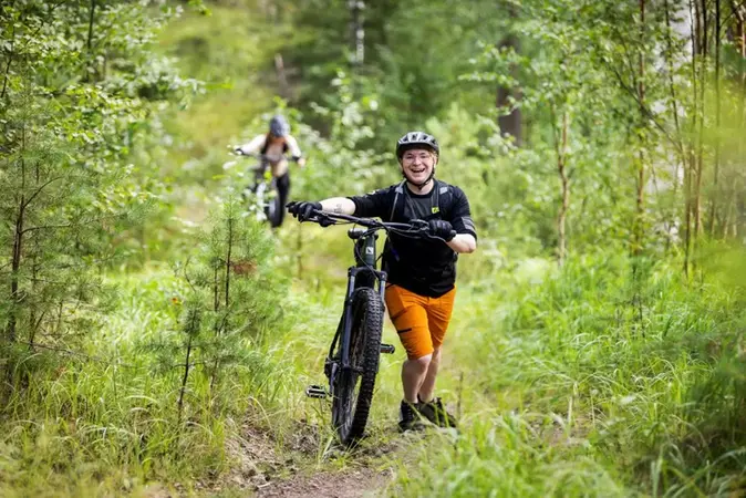 Glad kille som går med sin cykel