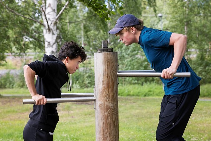 Två ungdomar använder en "maskin" på utegymmet på Vitberget.