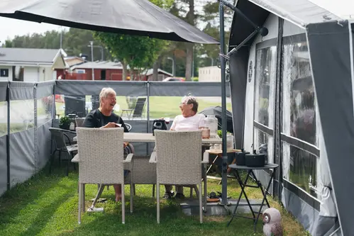 Ett par som sitter utanför sin husbil och fikar