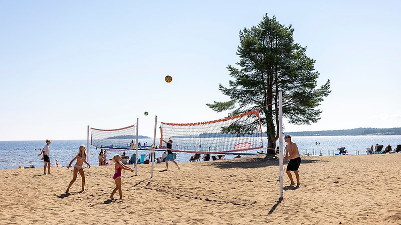 En familj spelar volleyboll på stranden.